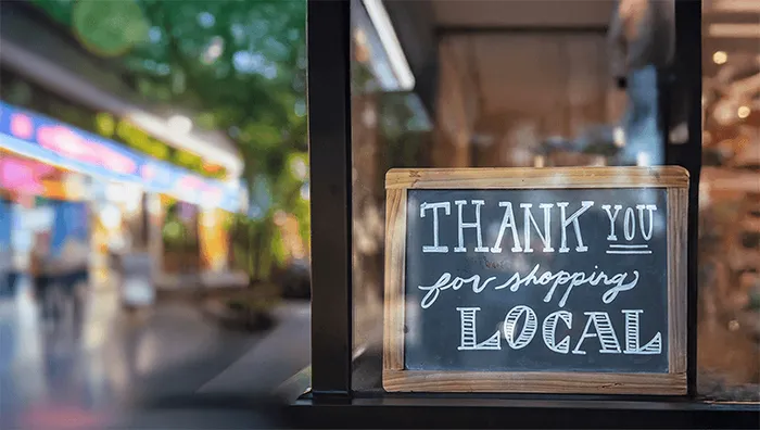 A chalkboard sign reading 'Thank you for shopping local' in a Delmarva storefront window